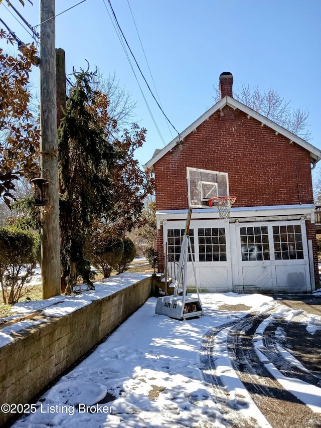 snow covered property featuring a garage and brick siding