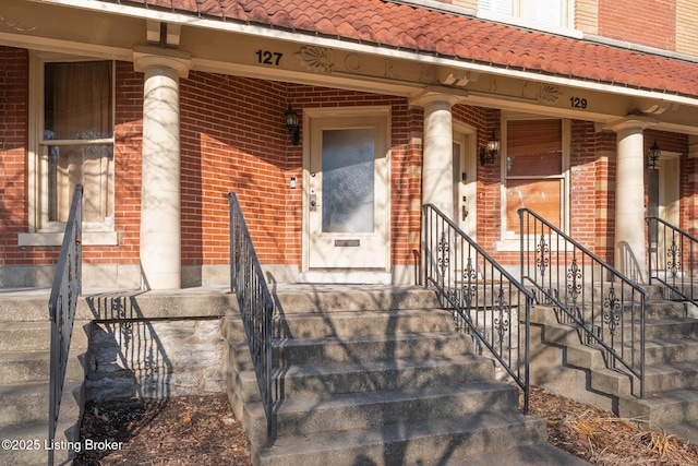 property entrance with a tiled roof and brick siding