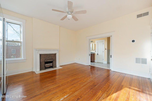 unfurnished living room with a fireplace with flush hearth, visible vents, and hardwood / wood-style floors