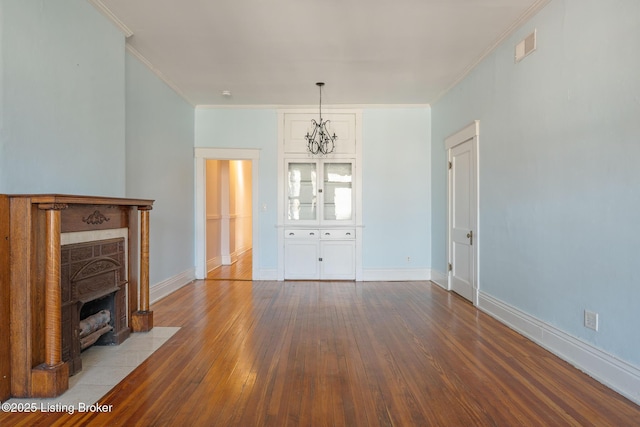 unfurnished living room featuring crown molding, hardwood / wood-style floors, a fireplace with flush hearth, and baseboards