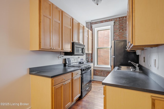 kitchen featuring black appliances, dark countertops, a sink, and baseboards