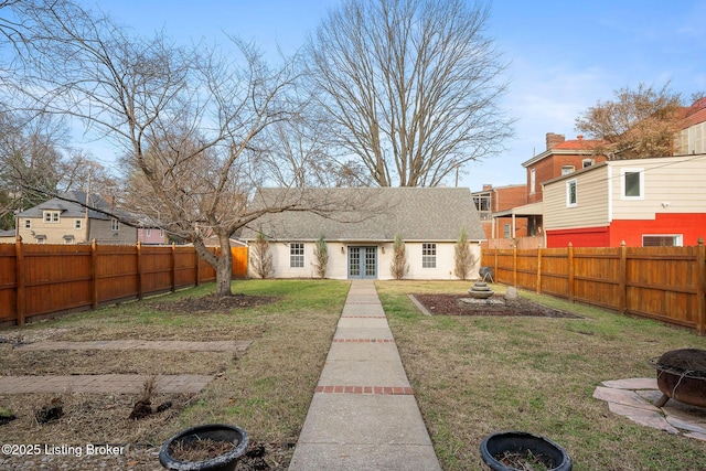 exterior space with french doors, a fenced backyard, a fire pit, and a front lawn