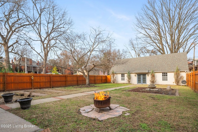 view of yard featuring a fire pit, french doors, and a fenced backyard