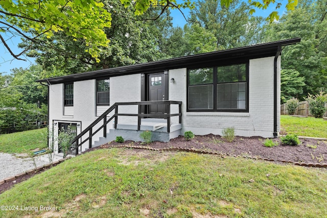 view of front of house featuring brick siding, a front lawn, and fence