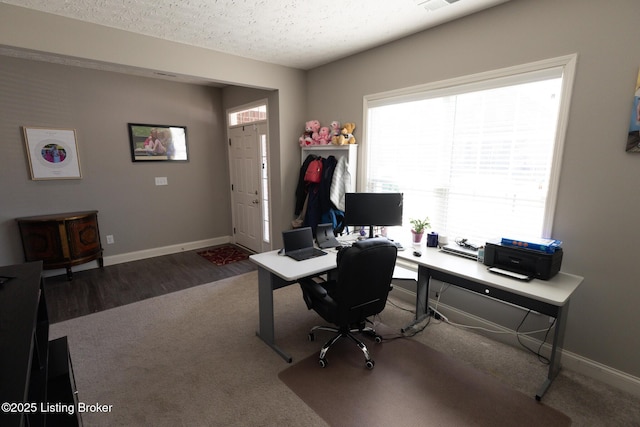 carpeted home office featuring visible vents, a textured ceiling, baseboards, and wood finished floors