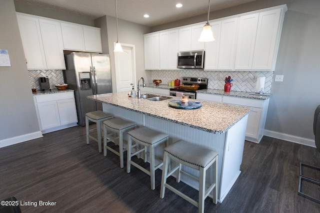 kitchen with baseboards, a breakfast bar area, appliances with stainless steel finishes, and dark wood-type flooring