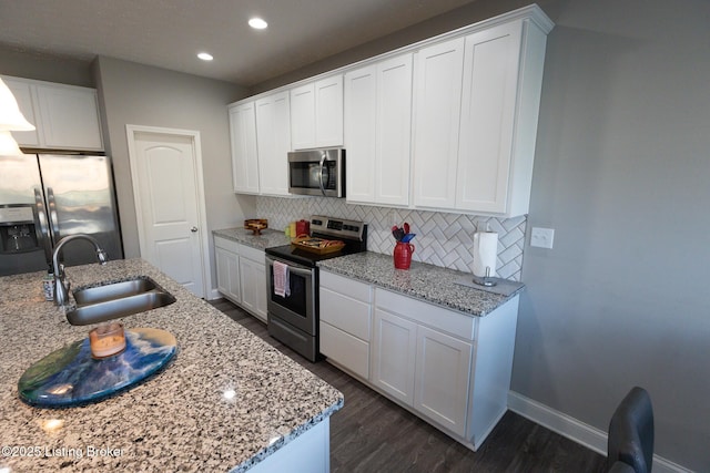 kitchen featuring appliances with stainless steel finishes, white cabinetry, a sink, and tasteful backsplash