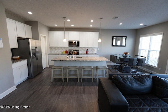 kitchen with decorative backsplash, appliances with stainless steel finishes, dark wood finished floors, and a sink