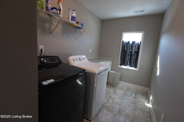 washroom featuring laundry area, baseboards, visible vents, independent washer and dryer, and a textured ceiling