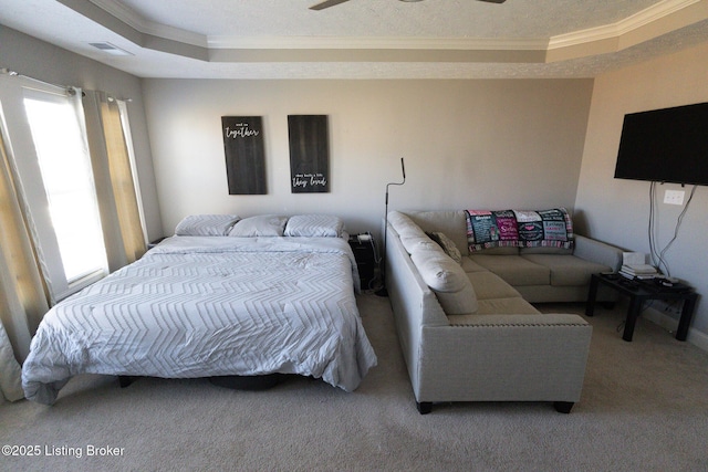 carpeted bedroom featuring a tray ceiling, visible vents, and crown molding