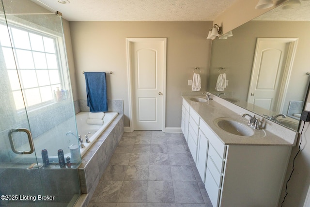 bathroom with a garden tub, a sink, a textured ceiling, and double vanity