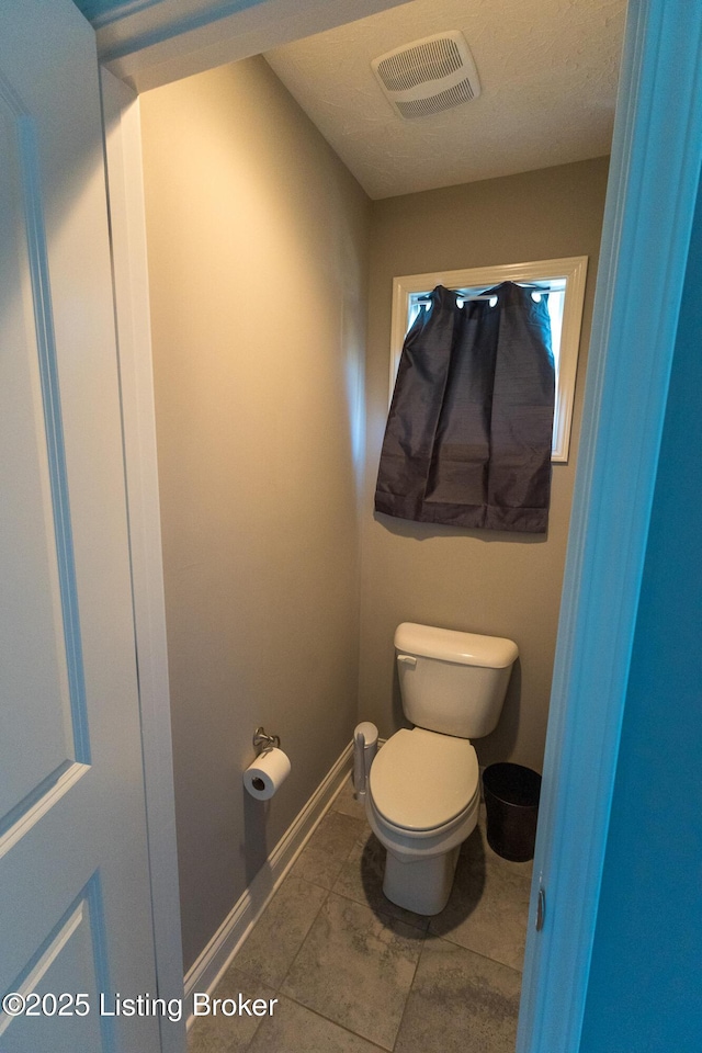 bathroom featuring baseboards, visible vents, toilet, and tile patterned floors