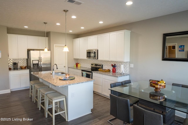 kitchen featuring white cabinetry, stainless steel appliances, dark wood finished floors, and a kitchen breakfast bar