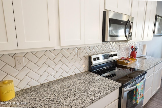 kitchen with white cabinetry, appliances with stainless steel finishes, decorative backsplash, and light stone counters