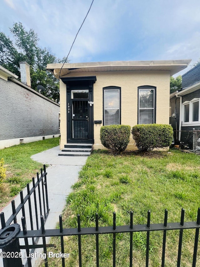 bungalow with entry steps, a front yard, fence, and brick siding