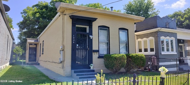 view of front facade with entry steps, a front lawn, and fence