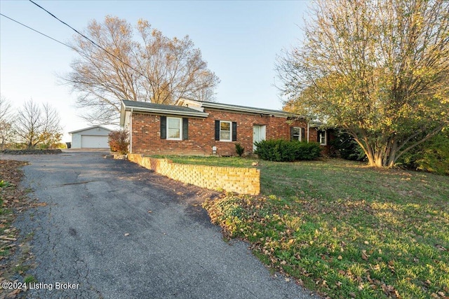 single story home with an outbuilding, brick siding, a front lawn, and a garage