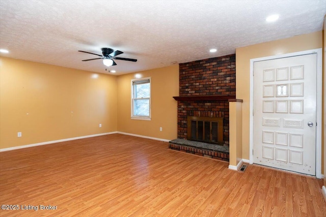 unfurnished living room with light wood-type flooring, a brick fireplace, and baseboards