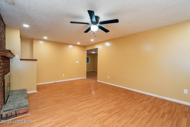 unfurnished living room with a textured ceiling, light wood finished floors, and a fireplace