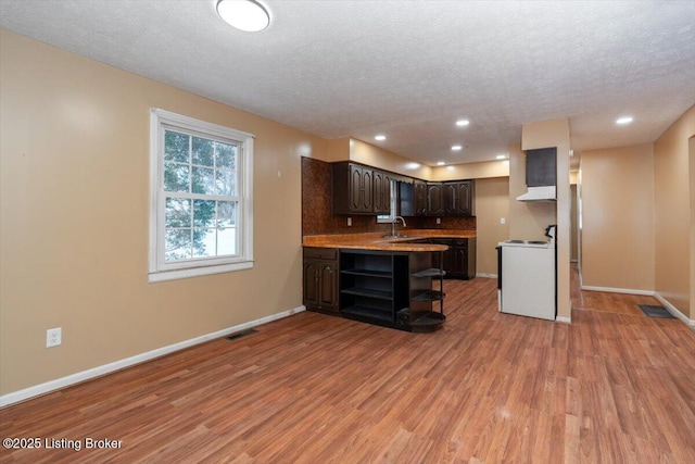 kitchen featuring range with electric stovetop, open shelves, visible vents, dark brown cabinets, and light wood-type flooring