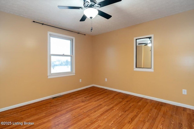 spare room featuring visible vents, light wood-style flooring, baseboards, and a textured ceiling