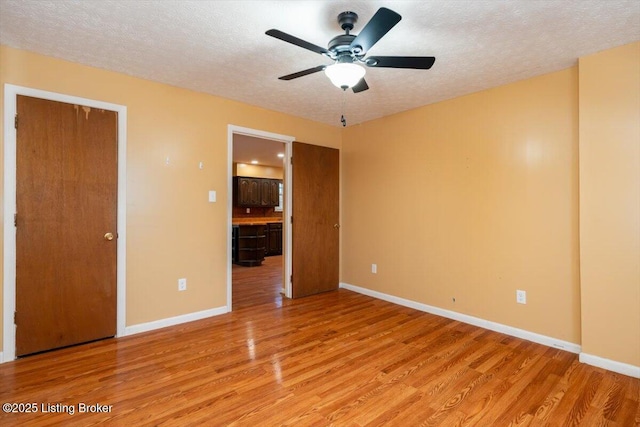 unfurnished bedroom with baseboards, light wood-style flooring, and a textured ceiling