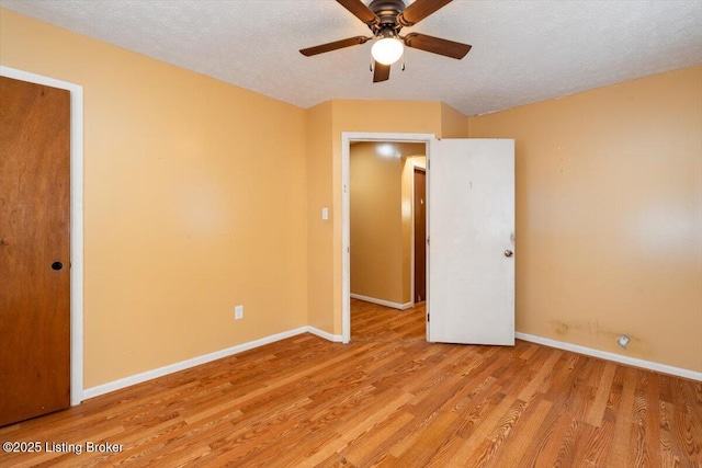 spare room with baseboards, ceiling fan, a textured ceiling, and light wood-style floors