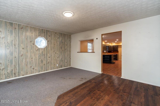 empty room featuring carpet floors, a healthy amount of sunlight, a textured ceiling, and wood finished floors