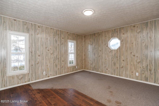 carpeted spare room with a textured ceiling and baseboards