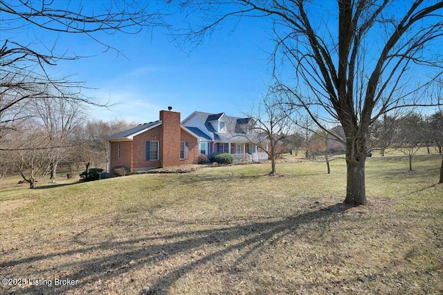 view of side of property with brick siding, a chimney, and a yard