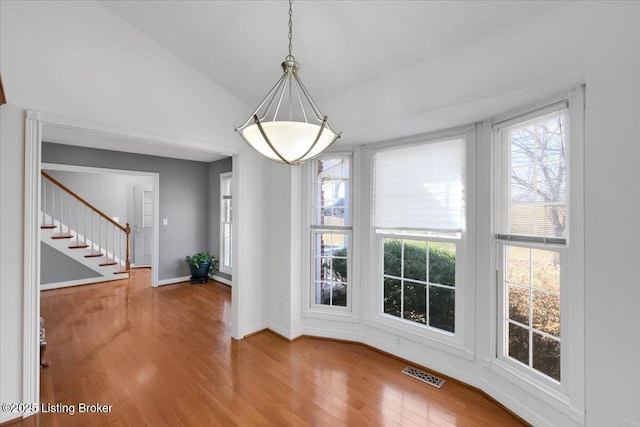 unfurnished dining area with plenty of natural light, wood-type flooring, stairs, and visible vents