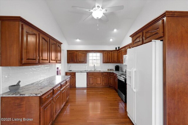 kitchen with lofted ceiling, light wood-style flooring, backsplash, a sink, and white appliances