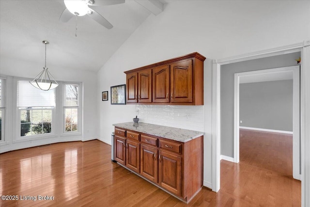 kitchen with light wood-style floors, beam ceiling, brown cabinetry, and backsplash