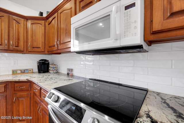 kitchen featuring white microwave, brown cabinetry, stainless steel range with electric stovetop, and decorative backsplash