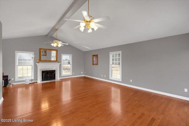 unfurnished living room featuring vaulted ceiling with beams, wood finished floors, and baseboards