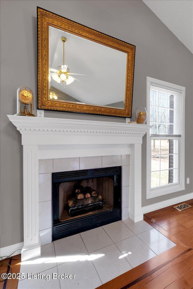 details featuring a ceiling fan, a fireplace, visible vents, and baseboards