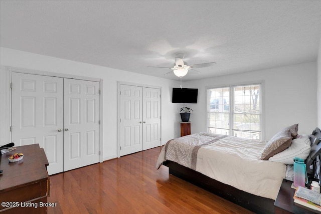 bedroom featuring ceiling fan, two closets, and wood finished floors