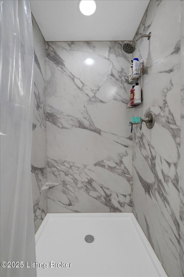 full bathroom featuring a marble finish shower and a textured ceiling