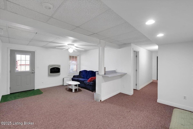 living area with baseboards, carpet floors, a drop ceiling, and heating unit