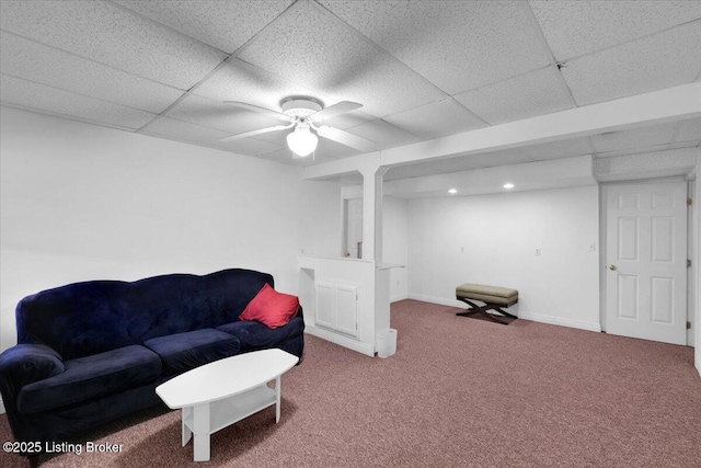 living area featuring a paneled ceiling, carpet flooring, ceiling fan, and baseboards