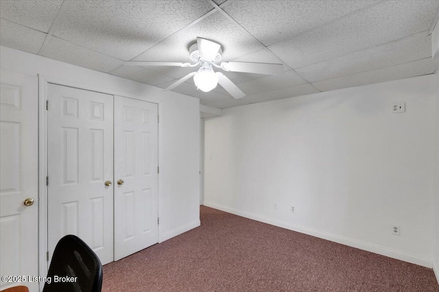 unfurnished bedroom with carpet floors, a closet, a drop ceiling, and baseboards