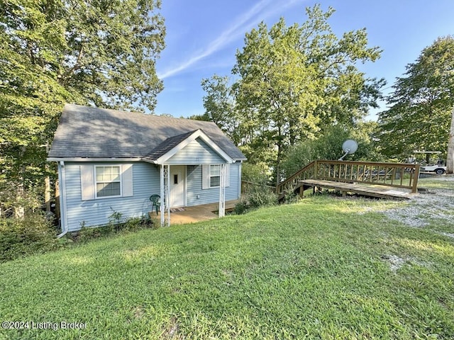 view of front of home featuring a patio area, roof with shingles, a deck, and a front yard