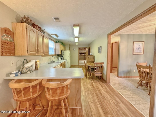 kitchen with light countertops, visible vents, a sink, a textured ceiling, and a peninsula