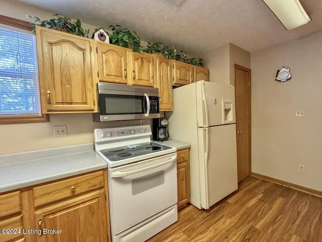 kitchen featuring light wood-type flooring, white appliances, light countertops, and a textured ceiling