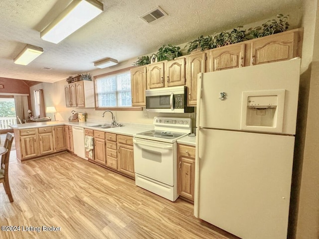 kitchen featuring light brown cabinets, white appliances, a sink, and visible vents