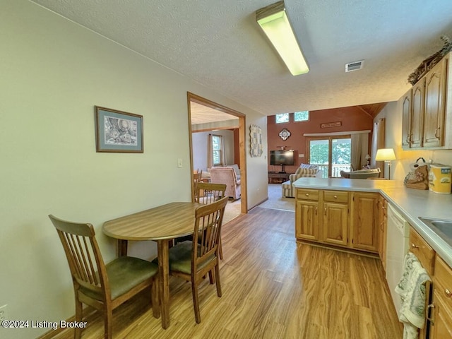 kitchen featuring visible vents, a peninsula, light countertops, a textured ceiling, and light wood-type flooring