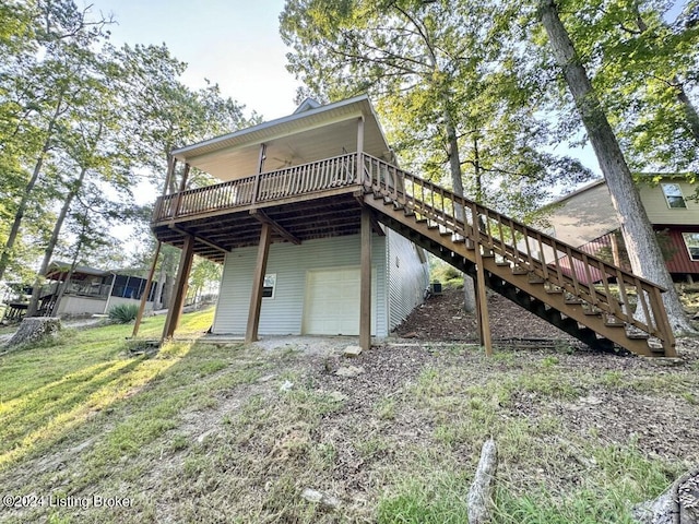 back of property with a lawn, a deck, a garage, driveway, and stairs