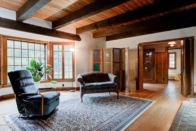 living room featuring hardwood / wood-style flooring, beamed ceiling, wood ceiling, and baseboards