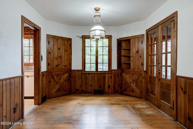 entrance foyer with hardwood / wood-style floors, a notable chandelier, and a wainscoted wall