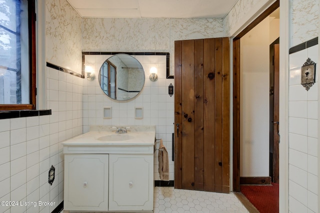 bathroom featuring tile patterned flooring, tile walls, vanity, and wallpapered walls